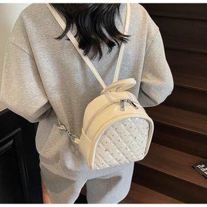 Detailed view of beige mini backpack featuring quilted diamond pattern and rhinestones
