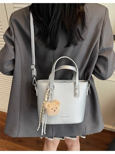 Silver lychee grain leather bucket bag with teddy bear charm shown on a model