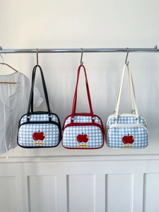 Three gingham tote bags with apple embroidery hanging on a rack in a minimalist room