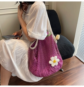 Detail of purple crochet net tote bag featuring white floral accents and inner lining