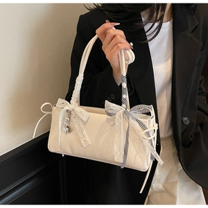 Detail view of cream crossbody bag featuring lace bow and heart metal pendant