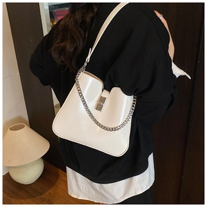 Detail of white glossy bucket bag showing silver chain strap and metal swivel lock closure