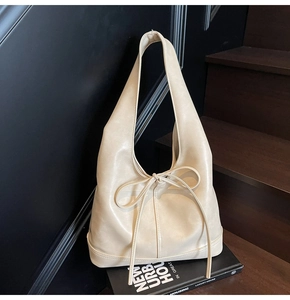 Détail du sac à bandoulière en cuir beige avec un long nœud décoratif élégant