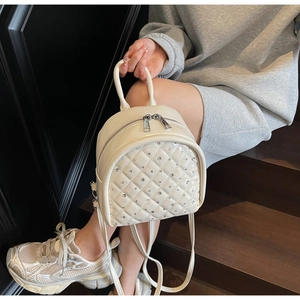 Detail of off-white quilted mini backpack with rhinestones on a female model