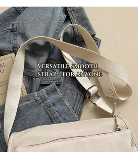 Detail of adjustable cream fabric shoulder strap and metal buckle on beige crossbody bag