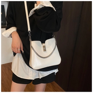 White leather bucket bag with silver chain detail and metal turn-lock on a model
