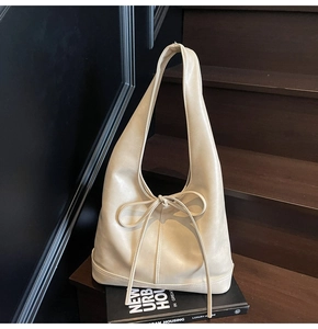 Détail d'un grand sac fourre-tout crème avec nœud décoratif et bandoulière large