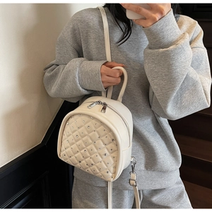 Detail of white quilted leather mini backpack with rhinestone studs and zipper closure