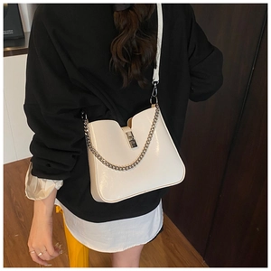 Detail of off-white bucket bag with thick metal chain and twist lock closure on a model
