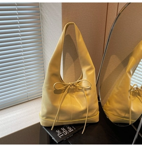 Détail d'un sac hobo en cuir jaune crème avec nœud décoratif et coutures de précision