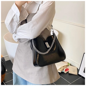 Close-up of shiny black bucket bag with vintage silver metal chain and buckle detail