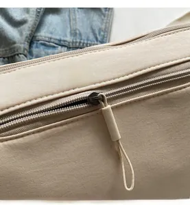 Close-up of smooth nylon zipper and extended puller on a stylish crossbody bag
