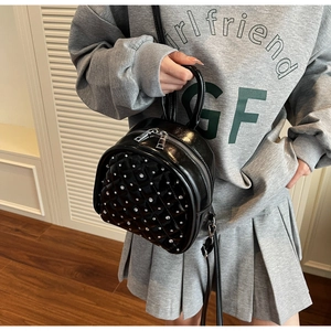 Close-up of black quilted patent leather backpack with sparkling rhinestones and silver zippers