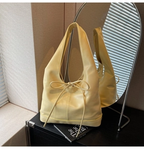 Détail du cabas en cuir jaune clair avec un nœud décoratif et une texture souple