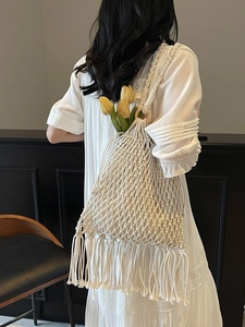 White woven bucket bag with tassels and wooden ring handles for summer casual beach style