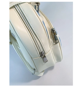 Detail view of double silver zippers and blue checkerboard print on white leather tote