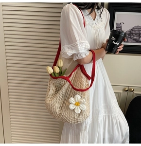 Detail of hollow woven tote bag with red handles and 3D daisy crochet flower decoration