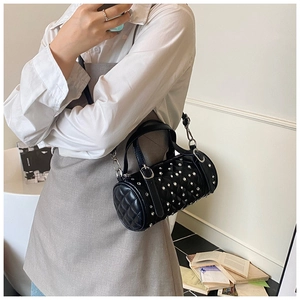 Détail du sac cylindrique noir avec surpiqûres en losanges et rivets argentés brillants