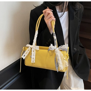 Detail of yellow pebble leather handbag with lace bow and checkered ribbon strap