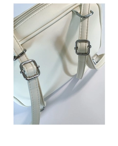 Detail of silver D-ring and adjustable buckle on a beige faux leather tote bag strap