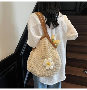Detail of crochet net tote bag with floral decoration and brown knit shoulder straps
