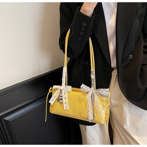 Detail of bright yellow leather shoulder bag with lace bows and heart metal charms