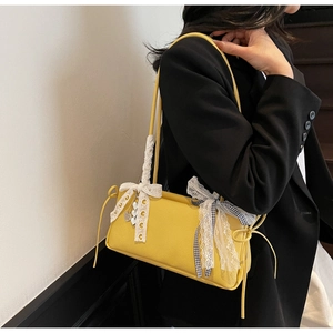 Detail of yellow lychee leather shoulder bag with white lace bows and heart charm