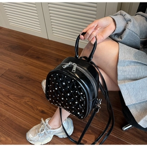 Detail of black quilted leather backpack with sparkling rhinestones and silver hardware