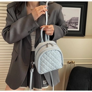 Close-up of light blue quilted mini backpack with rhinestones and silver zippers