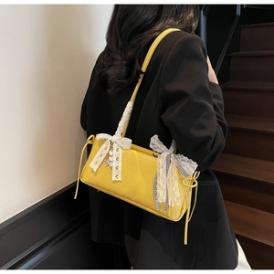 Detail of yellow lychee texture leather bag with lace bows and silver heart charm
