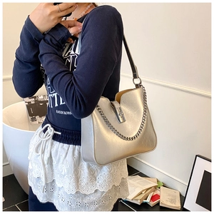 Detail view of silver metallic leather bucket bag with square turn-lock and chain strap