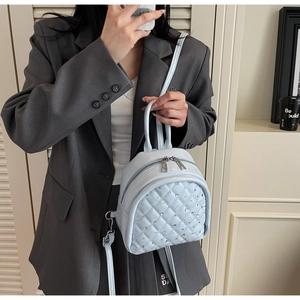 Detail of light blue quilted mini backpack with rhinestone decor on model