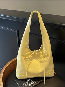 Sac fourre-tout minimaliste jaune clair en cuir avec nœud sur une chaise en bois