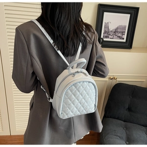 Detail of light blue quilted mini backpack with diamond stitching and rhinestone accents