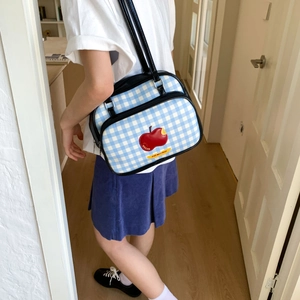 Detail of blue plaid tote bag featuring apple embroidery and Not Anxious slogan label