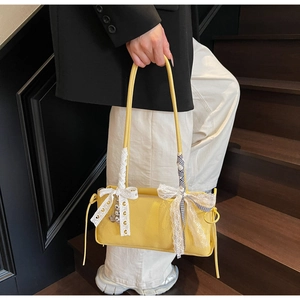 Detail of yellow lychee texture shoulder bag with white lace bow and heart pendant