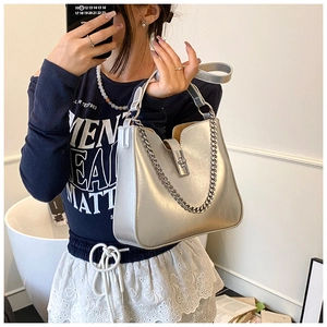 Detailed view of metallic silver bucket bag with chunky chain strap and metal lock closure