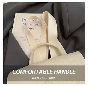 Close-up of cream textured leather bag handle and wide fabric shoulder strap details