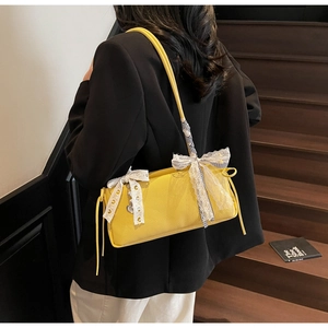 Detail of yellow lychee leather shoulder bag with white lace bow and heart charm