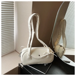 Detailansicht der cremeweißen Zylindertasche mit Schleife und flauschigem Cloud-Schultergurt