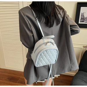 Close-up of light blue quilted mini backpack with sparkling rhinestones and silver zippers