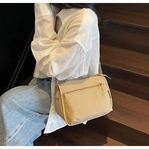 Detail view of beige canvas crossbody bag with multiple pockets and adjustable wide strap