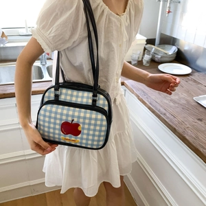 Detail of blue plaid tote bag with red apple patch and Not anxious text in kitchen