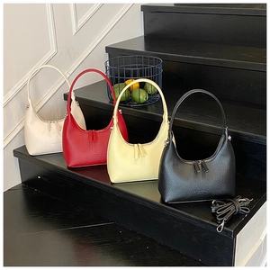 Borse hobo con trama litchi in crema, rosso, giallo e nero mostrate su un espositore