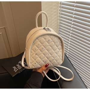 Macro detail of beige quilted PU leather backpack featuring sparkling diamond rhinestones