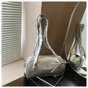 Makroaufnahme der silbernen Zylindertasche mit Schleifendetail und glänzendem Finish