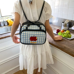 Detail of blue plaid backpack with apple graphic and black faux leather straps