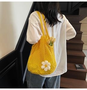 Detail of yellow woven mesh tote bag featuring white 3D daisies and floral accents