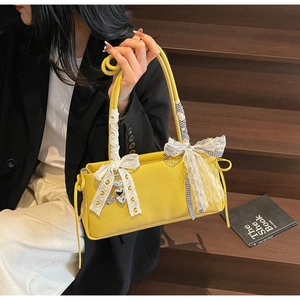 Close-up of yellow pebbled leather bag with white lace handles and silver heart charms