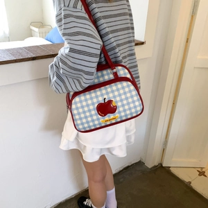 Detail view of retro blue and white checkered tote bag with red apple patch and leather straps